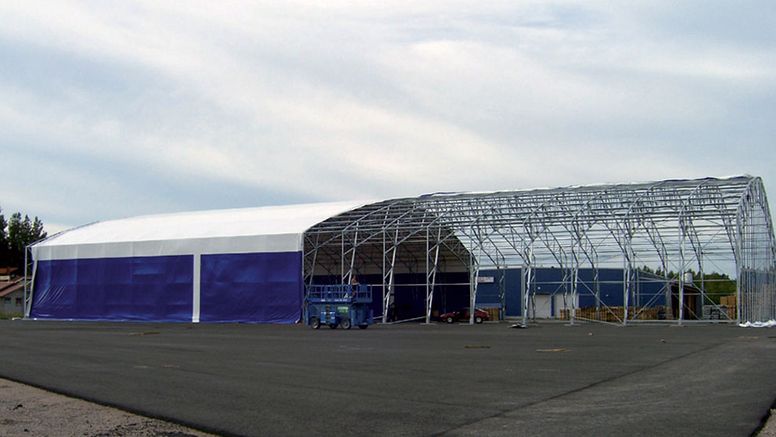 The roof covering of the steel-frame hall is spread out and finally tightened.